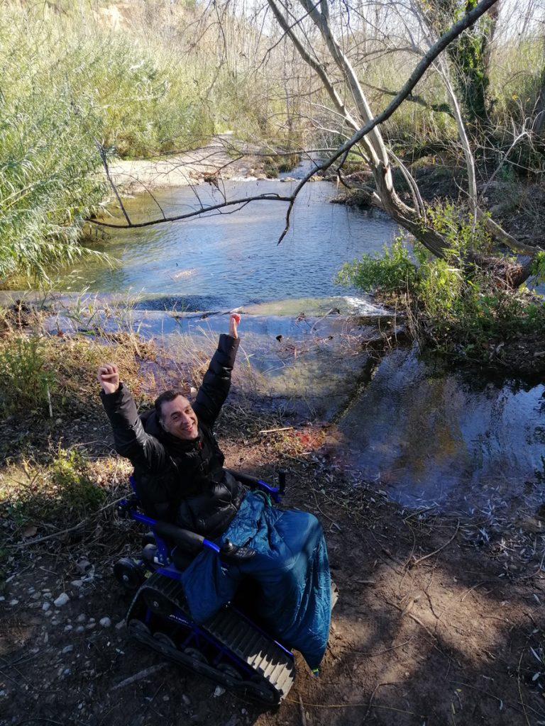 Foto de nuestro cliente feliz junto al rio en la silla de ruedas motorizada